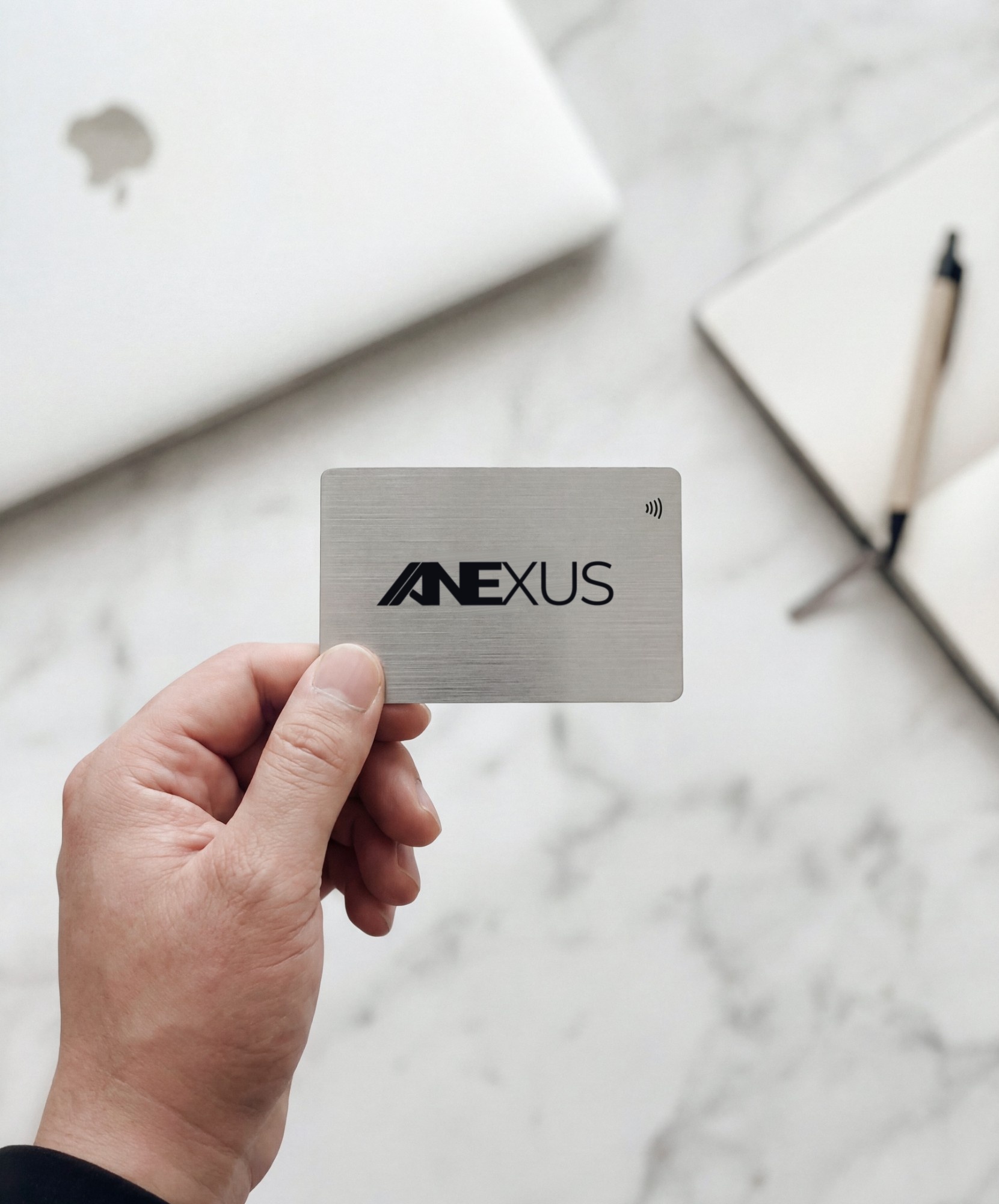 An engraved stainless steel Anexus NFC business card held in hand