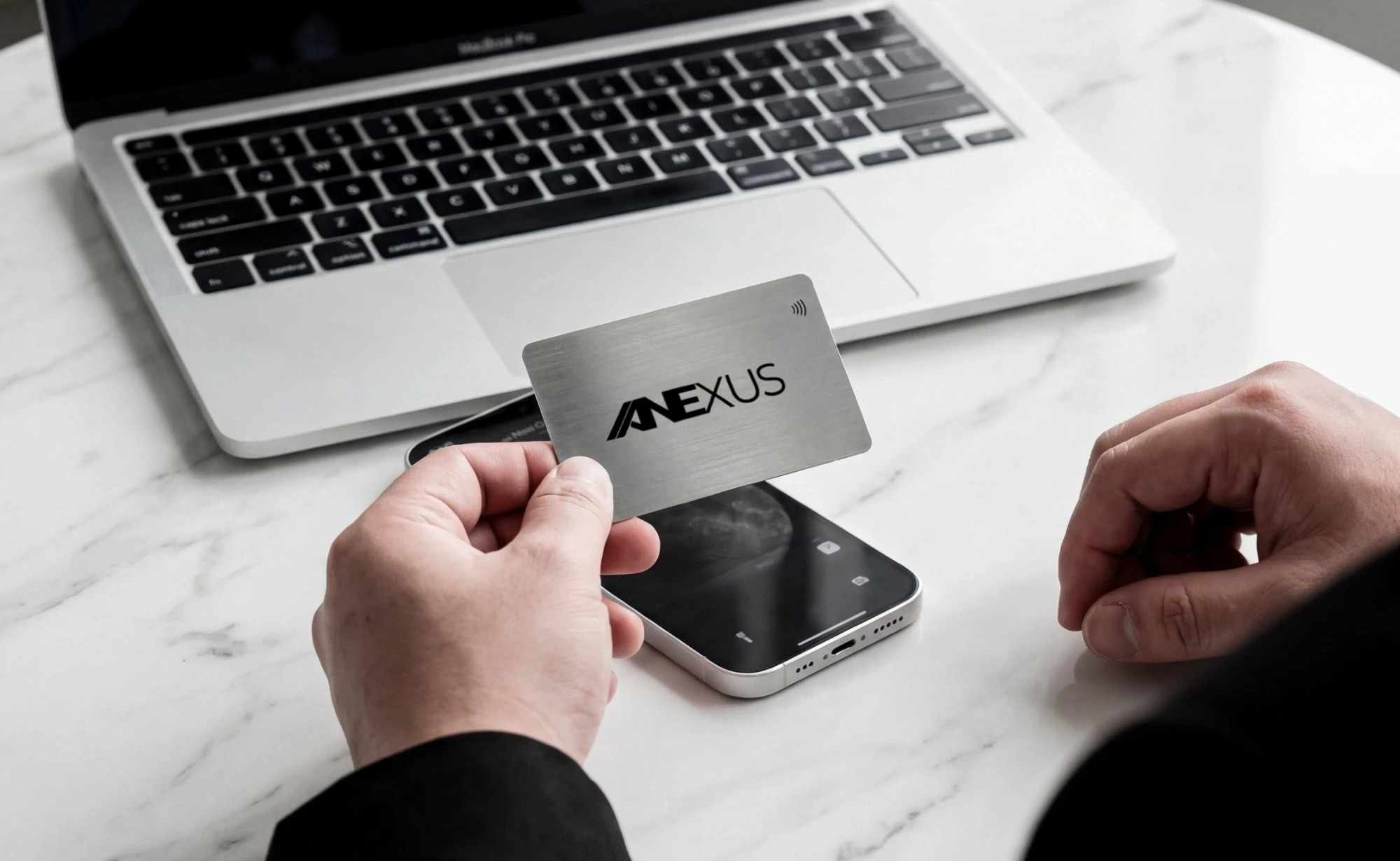 A brushed stainless steel Anexus NFC business card held above a phone, ready to tap